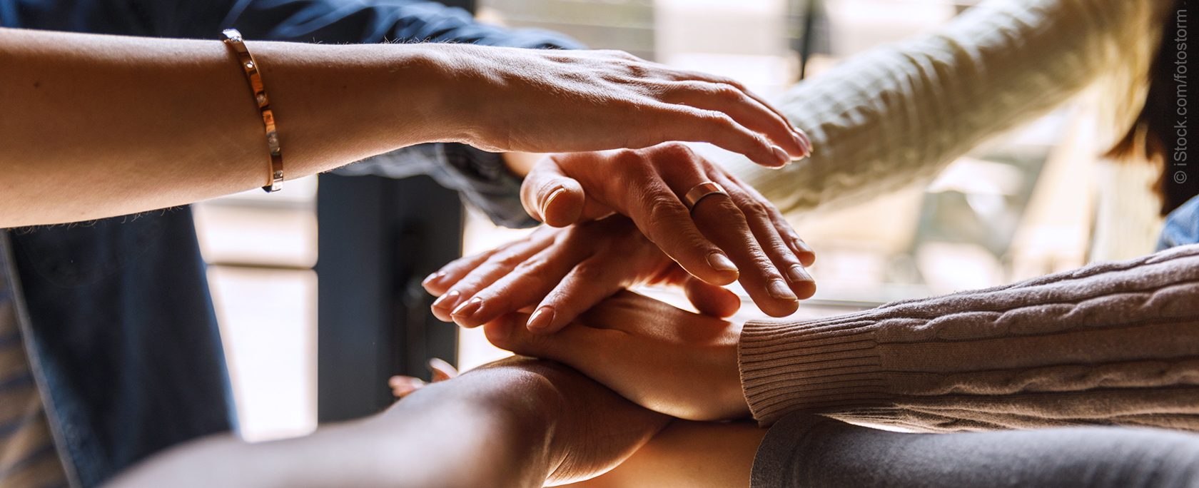 Close up shot of unrecognizable group of diverse individuals forming a united front, holding their hands stacked in a gesture of solidarity.